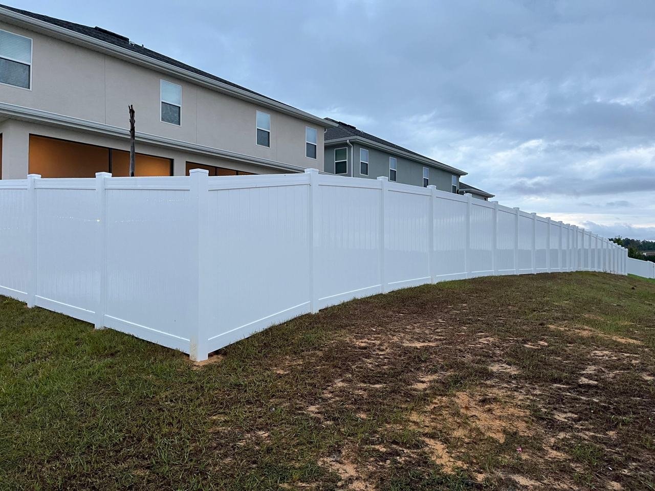 Long white vinyl privacy fence installed along a sloped yard in Orlando, FL