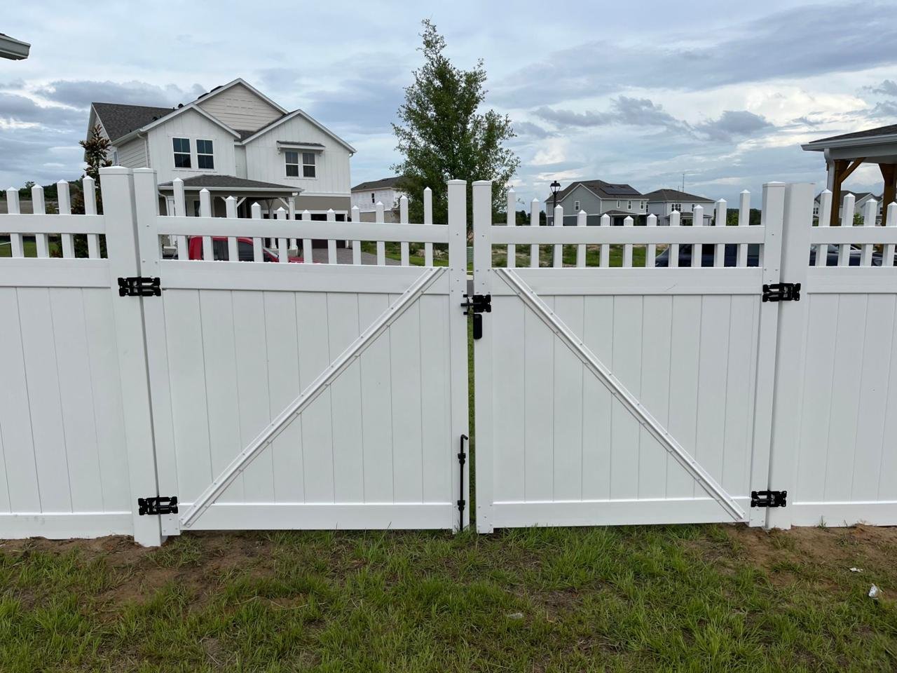 White vinyl double gate with a lattice-top fence and black hardware