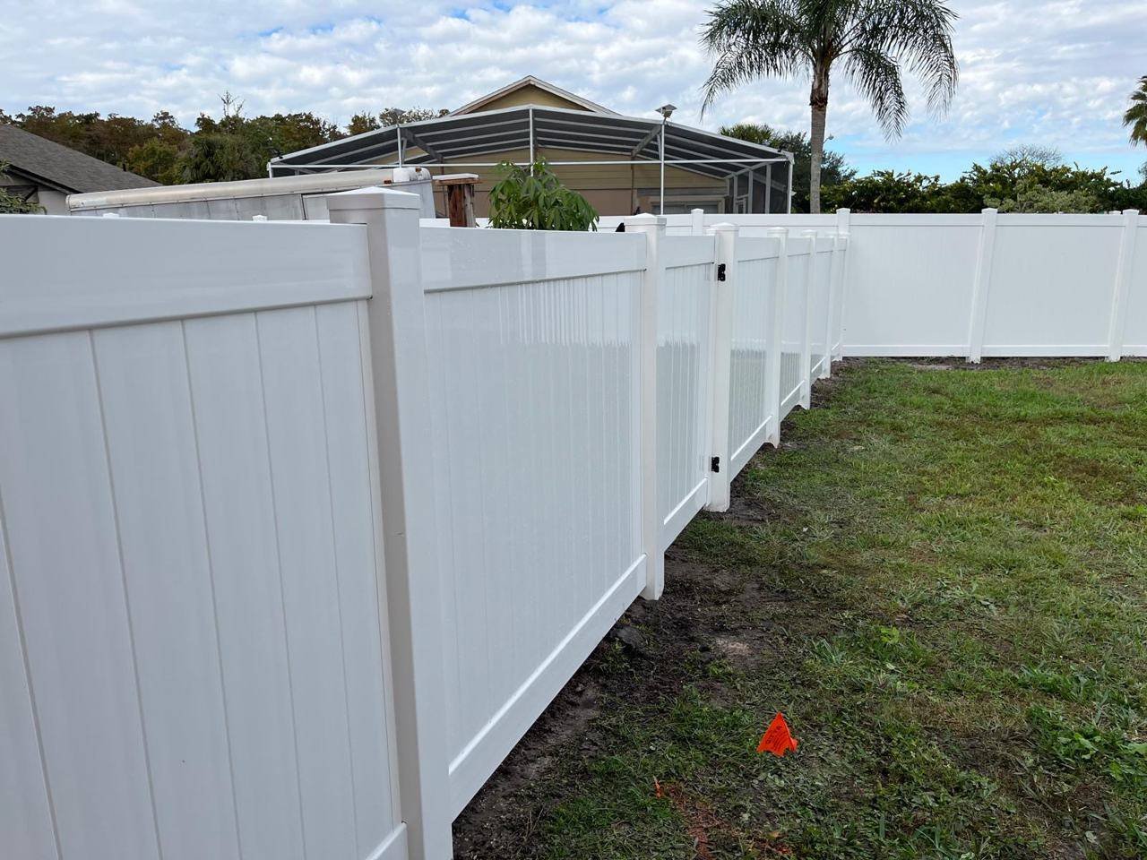 White vinyl fence installation with marked property line flags in Orlando, FL